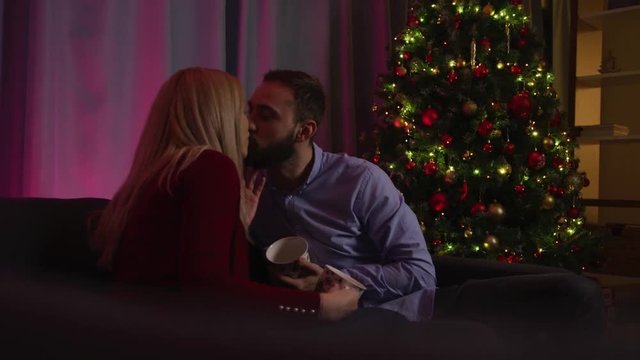 Couple kissing and drinking hot chocolate on Christmas Eve