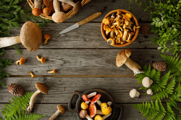 Mushrooms on old wooden background. Card on autumn or summertime. Forest harvest. Boletus, chanterelles, leaves, berries. Flat lay.