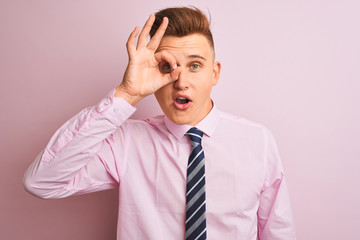 Young handsome businessman wearing shirt and tie standing over isolated pink background doing ok gesture shocked with surprised face, eye looking through fingers. Unbelieving expression.