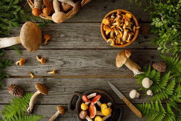 Mushrooms on old wooden background. Card on autumn or summertime. Forest harvest. Boletus, chanterelles, leaves, berries. Flat lay.