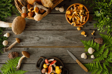 Mushrooms on old wooden background. Card on autumn or summertime. Forest harvest. Boletus, chanterelles, leaves, berries. Flat lay.