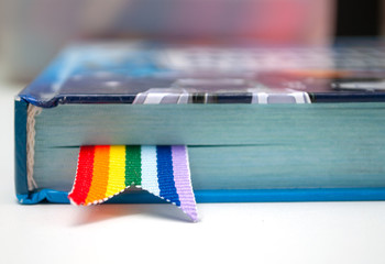 book with a bookmark of rainbow ribbon lying on the table