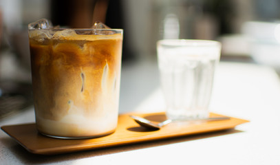 A glass of ice coffee on wooden tray