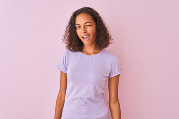 Fototapeta premium Young brazilian woman wearing t-shirt standing over isolated pink background winking looking at the camera with sexy expression, cheerful and happy face.
