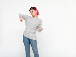 Naklejka premium Portrait of a knee-high pretty girl with red hair on a white background in a gray sweater and blue jeans. Standing right in front of the camera with emotions, talking, showing hands, smiling