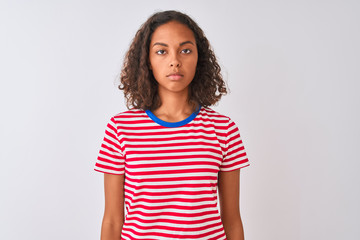 Young brazilian woman wearing red striped t-shirt standing over isolated white background Relaxed with serious expression on face. Simple and natural looking at the camera.