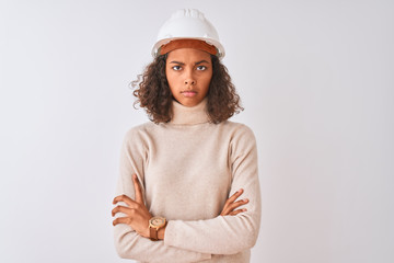 Young brazilian architect woman wearing security helmet over isolated white background skeptic and...