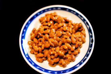 Closeup macro of Asian Japanese natto fermented soy dish meal sticky slimy texture in plate bowl with black background
