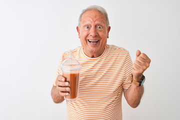 Senior man wearing striped t-shirt drinking tomato smoothie over isolated white background screaming proud and celebrating victory and success very excited, cheering emotion