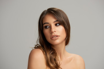 Naklejka premium Headshot of beautiful Caucasian brunette posing in front of grey background. Beauty photography.