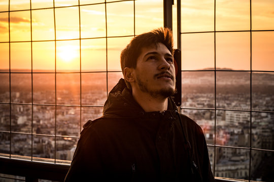 A young men in the top of the Eiffel Tower looking the sky
