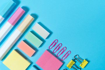 Stationery, marker and paperclip on blue pastel background