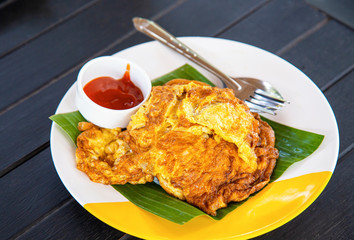 Egg omelet with ketchup on wood table