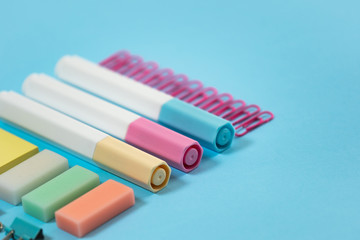 Stationery, marker and paperclip on blue pastel background