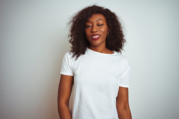 Young african american woman wearing t-shirt standing over isolated white background winking looking at the camera with sexy expression, cheerful and happy face.