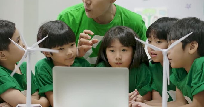 Informative ecology teacher use laptop computer having lesson about recycling to elementary students in class at the elementary school.