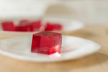 Red jelly cubes on white plate background. Berry sweet pieces of jelly. Homemade red cherry gelatin...