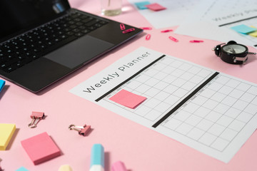 Fototapeta premium Laptop, stationery and planner on pink pastel background