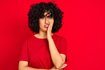 Fototapeta na wymiar Young arab woman with curly hair wearing casual t-shirt over isolated red background thinking looking tired and bored with depression problems with crossed arms.