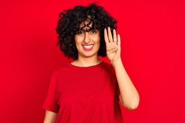 Fototapeta na wymiar Young arab woman with curly hair wearing casual t-shirt over isolated red background showing and pointing up with fingers number four while smiling confident and happy.