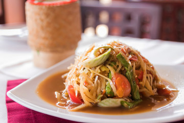 Papaya salad with salted crab and fermented fish sauce served with sticky rice in Kratip (northern and northeastern Thais as containers for sticky rice).