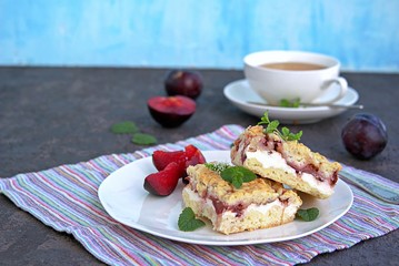 Sliced shortbread cake with curd cream and plum on a white plate. Sweet cakes. Harvest plums.