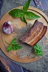 Delicious smoked bacon with spices,herbs and garlic on wooden background.