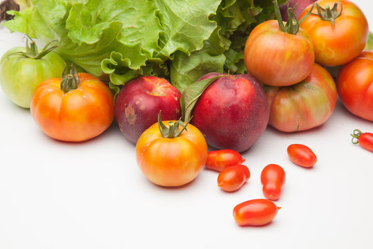Lechuga verde y distintas frutas, tomates, cherri y de los otros, nectarinas todo sobre fondo blanco