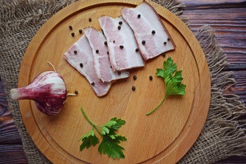 Delicious smoked bacon with spices,herbs and garlic on wooden background.
