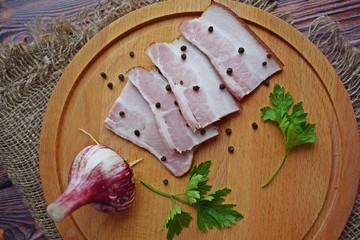 Delicious smoked bacon with spices,herbs and garlic on wooden background.