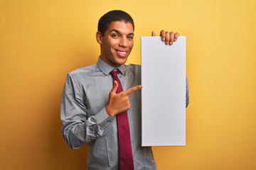 Young handsome arab businessman holding banner standing over isolated yellow background very happy pointing with hand and finger