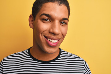 Young handsome arab man wearing navy striped t-shirt over isolated yellow background with a happy face standing and smiling with a confident smile showing teeth