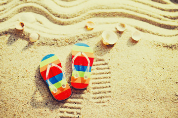 Fototapeta na wymiar Vacation background with bright flip flops on sand, top view