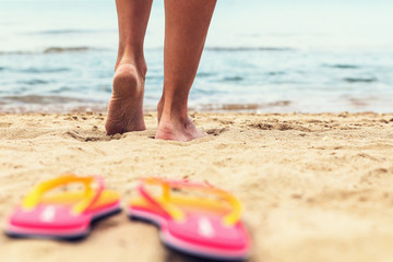 Feet on the sand close up. The girl goes to the sea along the beach
