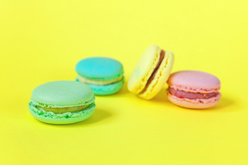 Fototapeta na wymiar Sweet almond colorful unicorn pink blue yellow green macaron or macaroon dessert cake isolated on trendy yellow modern fashion background. French sweet cookie. Minimal food bakery concept. Copy space