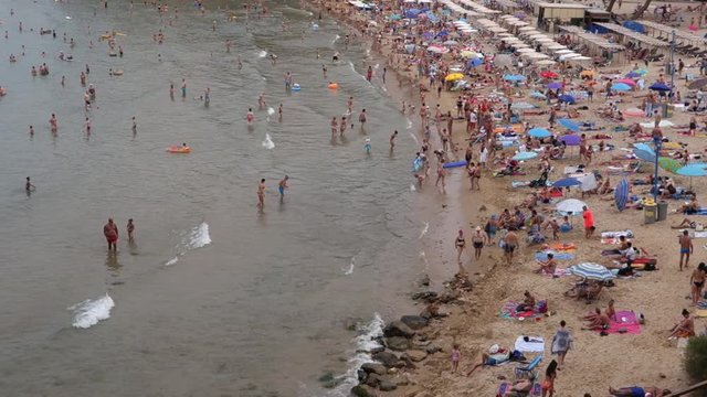 People relaxing and having fun on the beach to have their holidays at the coast of Salou, Spain, a famous tourist destination