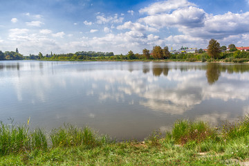 Pond on the outskirts of town under summer sky.