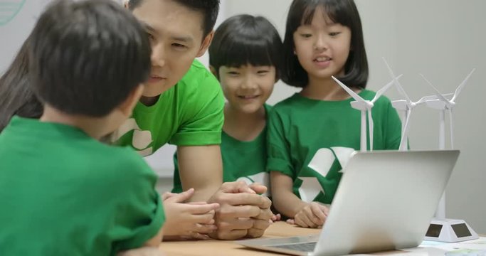 Informative ecology teacher use laptop computer having lesson about recycling to elementary students in class at the elementary school.