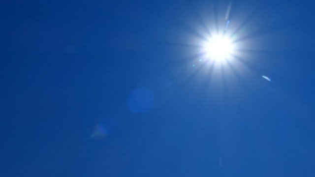 Bright scorching sun against the blue sky. A hot, sunny day. The sun is at its zenith.