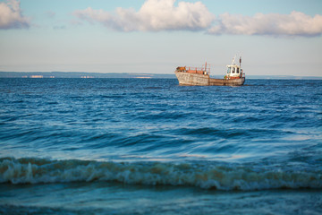 Obraz premium old fishing boat going on the sea waves