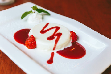 Close-up Milk Pudding served with strawberry sauce, whip cream, sliced fresh strawberry and mint.