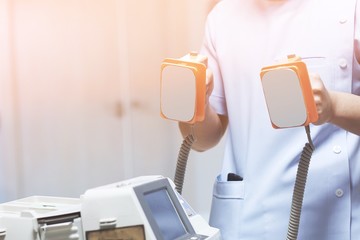 The doctor is giving a defibrillators to save the patient's life in the hospital.
