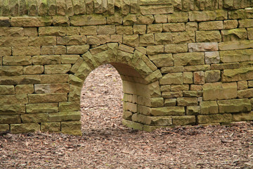 A Stone Built Wall with a Small Archway Through It.