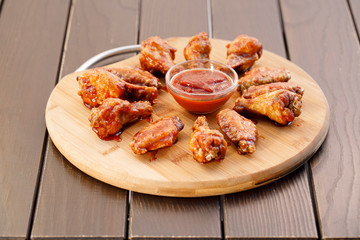 Spicy deep fried chicken wings and legs with dipping sauce on wooden plate , wood background.