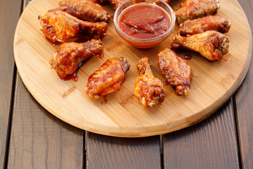 Spicy deep fried chicken wings and legs with dipping sauce on wooden plate , wood background.