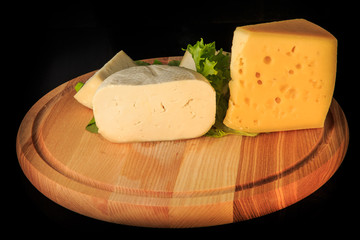 closeup round wooden board with assorted hard cheese