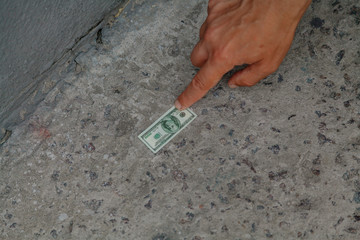 Hand reaches for bill on concrete