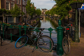 Fototapeta na wymiar Leiden, Holland, Netherlands, April 18, 2019, bicycles parked on a bridge and along a street, canal in Leiden old town. Flowers in a flowerbeds, boats on the water.