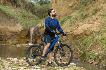 Obraz premium Cyclist in shorts and jersey on a modern carbon hardtail bike with an air suspension fork rides off-road on the orange-red hills at sunset evening in summer 