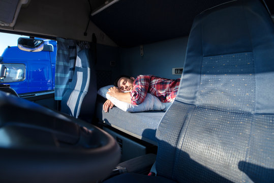 Truck driver sleeping on bed inside truck cabin interior. Trucker lifestyle and people sleeping at job.